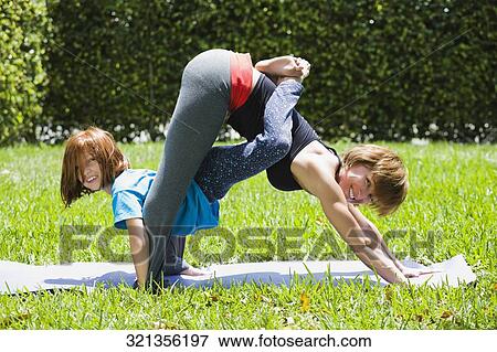 Portrait of a mid adult woman with her daughter practicing yoga View Large Photo Image Stock Photo - Portrait of a mid adult woman with her daughter practicing yoga. Fotosearch