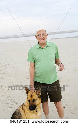 Portrait of a senior man standing with his dog on the beach View Large Photo Image Stock Image - Portrait of a senior man standing with his dog on the beach. Fotosearch