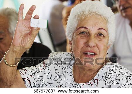 Stock Photo - Portrait of a senior woman showing a domino. Fotosearch