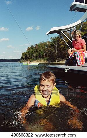 Portrait of a teenage boy swimming in a lake with her mother in the background, West Yellowstone, Montana, USA View Large Photo Image Stock Image - Portrait of a teenage boy swimming in a lake with her mother in the background, West Yellowstone, Montana, USA. Fotosearch