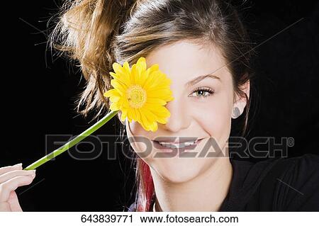 Portrait of a teenage girl covering her eye with a flower View Large Photo Image Stock Image - Portrait of a teenage girl covering her eye with a flower. Fotosearch