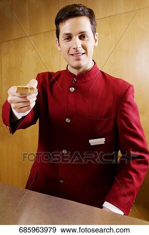 Stock Photo - Portrait of a waiter holding a cardkey and smiling. Fotosearch