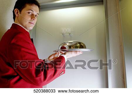 Portrait of a waiter holding a domed tray View Large Photo Image Stock Image - Portrait of a waiter holding a domed tray. Fotosearch