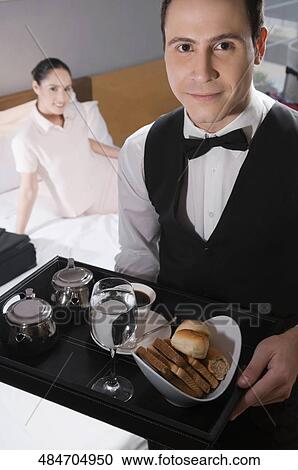 Portrait of a waiter holding a breakfast tray with a businesswoman in the background View Large Photo Image Stock Image - Portrait of a waiter holding a breakfast tray with a businesswoman in the background. Fotosearch