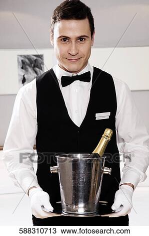 Portrait of a waiter holding a champagne bottle in an ice bucket View Large Photo Image Stock Image - Portrait of a waiter holding a champagne bottle in an ice bucket. Fotosearch