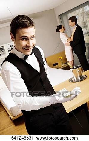 Portrait of a waiter holding us paper currency and smiling View Large Photo Image Stock Image - Portrait of a waiter holding us paper currency and smiling. Fotosearch