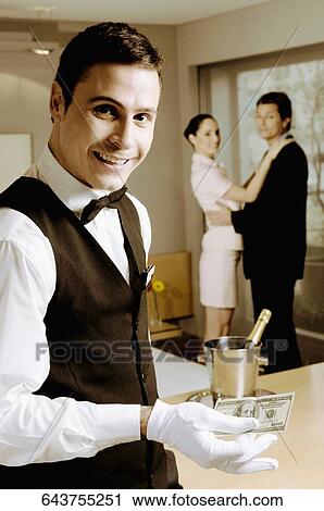 Portrait of a waiter holding US paper currency View Large Photo Image Stock Image - Portrait of a waiter holding US paper currency. Fotosearch