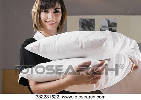 Stock Image - Portrait of a waitress carrying pillows. Fotosearch