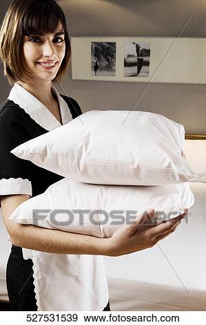 Stock Photo - Portrait of a waitress holding pillows. Fotosearch