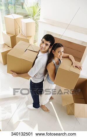 Portrait of a young couple holding cardboard boxes and smiling View Large Photo Image Stock Image - Portrait of a young couple holding cardboard boxes and smiling. Fotosearch