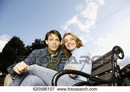 Portrait of a young couple sitting on a bench View Large Photo Image Stock Photo - Portrait of a young couple sitting on a bench. Fotosearch