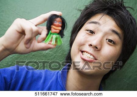 Stock Photo - Portrait of a young man holding a doll. Fotosearch