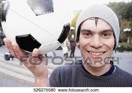 Portrait of a young man holding a soccer ball and smiling View Large Photo Image Stock Image - Portrait of a young man holding a soccer ball and smiling. Fotosearch