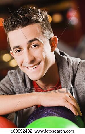 Portrait of a young man holding a bowling ball and smiling View Large Photo Image Stock Image - Portrait of a young man holding a bowling ball and smiling. Fotosearch