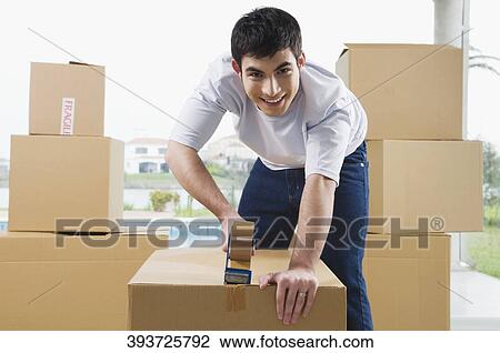Portrait of a young man pasting adhesive tape on a cardboard box View Large Photo Image Stock Image - Portrait of a young man pasting adhesive tape on a cardboard box. Fotosearch