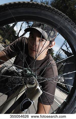 Portrait of a young man repairing a bicycle View Large Photo Image Stock Photograph - Portrait of a young man repairing a bicycle. Fotosearch