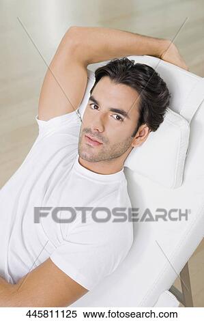 Portrait of a young man resting on a reclining chair View Large Photo Image Stock Photography - Portrait of a young man resting on a reclining chair. Fotosearch