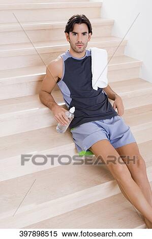 Portrait of a young man sitting on staircase and holding a water bottle View Large Photo Image Stock Photography - Portrait of a young man sitting on staircase and holding a water bottle. Fotosearch