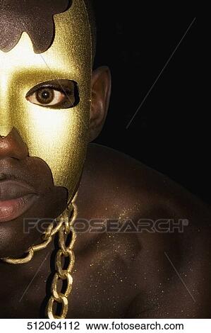 Stock Image - Portrait of a young man with painted face wearing a chain, Gay Pride Parade, New York City, New York State, USA. Fotosearch
