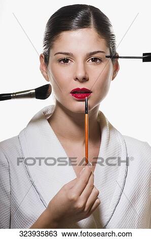 Portrait of a young woman applying make-up View Large Photo Image Stock Image - Portrait of a young woman applying make-up. Fotosearch