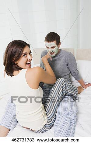 Portrait of a young woman applying facial mask on a young man's face View Large Photo Image Stock Image - Portrait of a young woman applying facial mask on a young man's face. Fotosearch