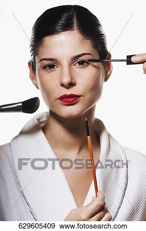 Stock Photo - Portrait of a young woman applying make-up. Fotosearch