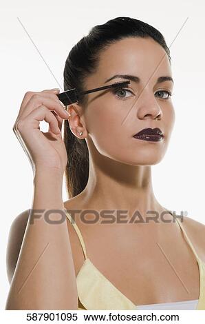 Portrait of a young woman applying mascara View Large Photo Image Stock Photography - Portrait of a young woman applying mascara. Fotosearch