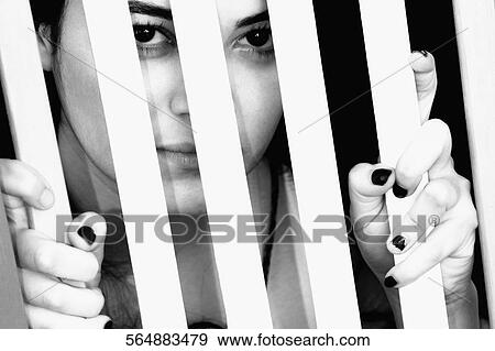 Portrait of a young woman behind a window bars View Large Photo Image Stock Photo - Portrait of a young woman behind a window bars. Fotosearch