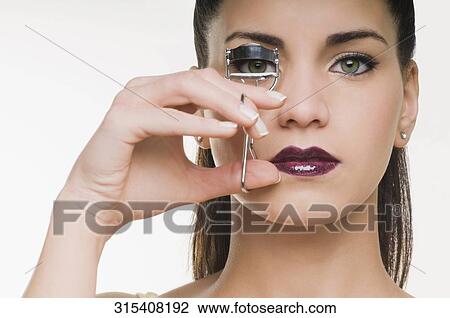 Portrait of a young woman curling eyelashes View Large Photo Image Stock Image - Portrait of a young woman curling eyelashes. Fotosearch