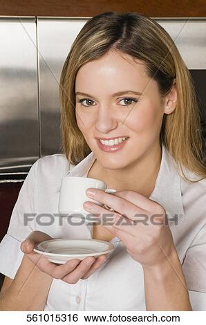 Portrait of a young woman drinking coffee and smiling View Large Photo Image Stock Photograph - Portrait of a young woman drinking coffee and smiling. Fotosearch