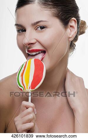 Portrait of a young woman eating a lollipop View Large Photo Image Stock Photo - Portrait of a young woman eating a lollipop. Fotosearch