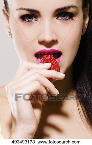 Portrait of a young woman eating a strawberry View Large Photo Image Stock Photo - Portrait of a young woman eating a strawberry. Fotosearch