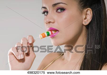 Portrait of a young woman eating a lollipop View Large Photo Image Stock Photography - Portrait of a young woman eating a lollipop. Fotosearch