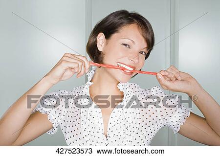 Portrait of a young woman eating licorice candy and smiling View Large Photo Image Stock Image - Portrait of a young woman eating licorice candy and smiling. Fotosearch