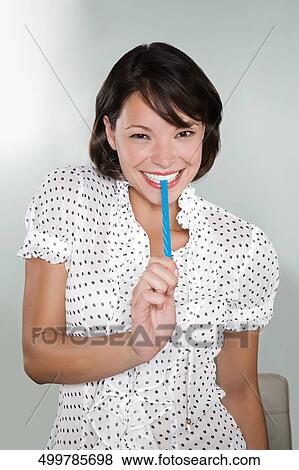 Stock Photo - Portrait of a young woman eating licorice candy and smiling. Fotosearch