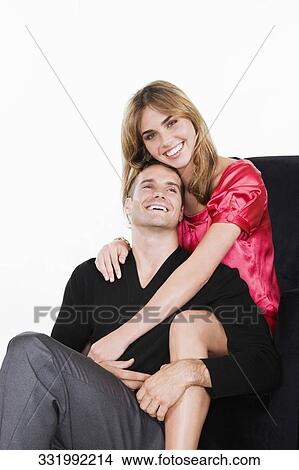 Portrait of a young woman embracing a young man from behind and smiling View Large Photo Image Picture - Portrait of a young woman embracing a young man from behind and smiling. Fotosearch