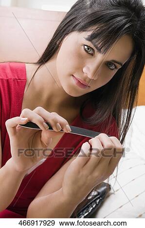 Portrait of a young woman filing her nails View Large Photo Image Stock Photo - Portrait of a young woman filing her nails. Fotosearch