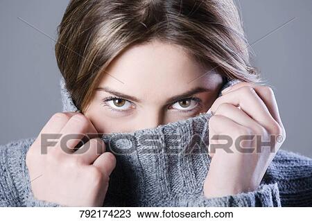 Portrait of a young woman hiding her face with turtleneck collar View Large Photo Image Stock Image - Portrait of a young woman hiding her face with turtleneck collar. Fotosearch