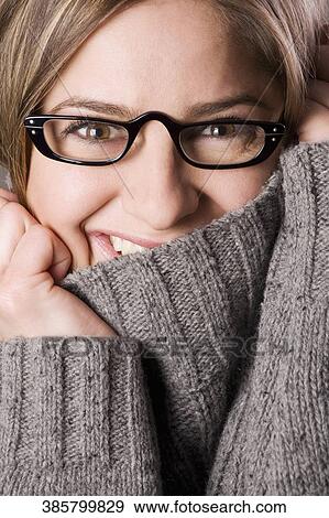 Portrait of a young woman hiding her face with turtleneck collar and smiling View Large Photo Image Stock Photo - Portrait of a young woman hiding her face with turtleneck collar and smiling. Fotosearch