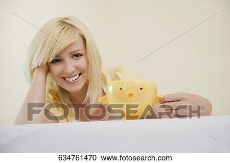 Stock Image - Portrait of a young woman holding a cup and smiling. Fotosearch