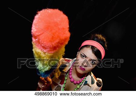 Stock Image - Portrait of a young woman holding a duster. Fotosearch