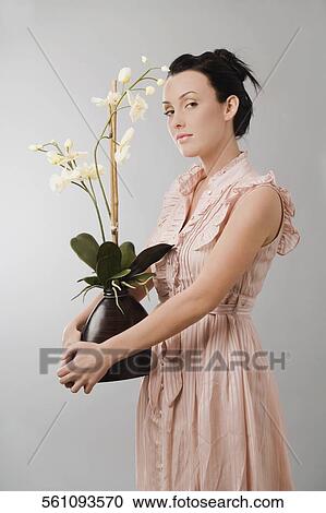 Stock Image - Portrait of a young woman holding a flower pot. Fotosearch