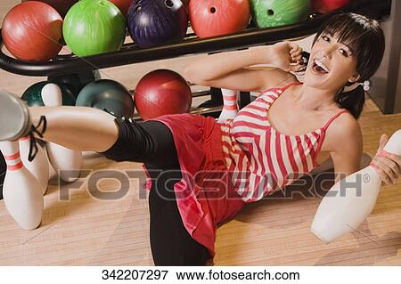 Portrait of a young woman holding a bowling pin and smiling View Large Photo Image Stock Photo - Portrait of a young woman holding a bowling pin and smiling. Fotosearch