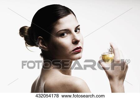 Portrait of a young woman holding a perfume bottle View Large Photo Image Stock Photo - Portrait of a young woman holding a perfume bottle. Fotosearch