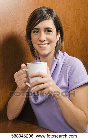 Portrait of a young woman holding a coffee cup View Large Photo Image Stock Photograph - Portrait of a young woman holding a coffee cup. Fotosearch