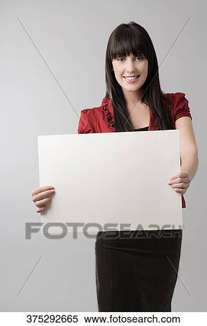 Stock Photography - Portrait of a young woman holding a sheet of paper and smiling. Fotosearch