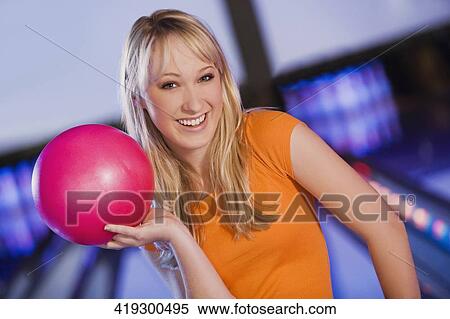 Stock Photography - Portrait of a young woman holding a bowling ball. Fotosearch