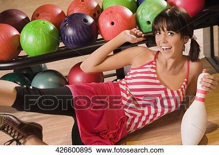 Portrait of a young woman holding a bowling pin and smiling View Large Photo Image Stock Photography - Portrait of a young woman holding a bowling pin and smiling. Fotosearch