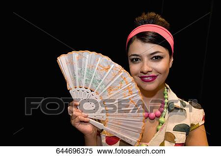 Portrait of a young woman holding a folding fan and smiling View Large Photo Image Stock Photography - Portrait of a young woman holding a folding fan and smiling. Fotosearch