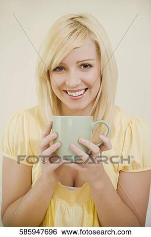 Stock Photograph - Portrait of a young woman holding a tea cup and smiling. Fotosearch